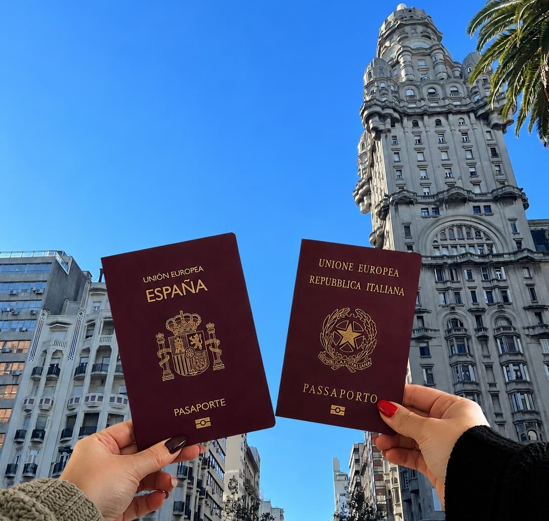 Pasaportes de España e Italia con el Palacio Salvo de Montevideo al fondo.
